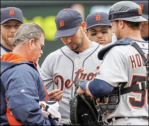 A trainer checks Detroit pitcher Anibal Sanchez’s hand in the third inning. He had not allowed a hit but had to leave the game.