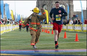 Matthew Riggle, left, Perkins Township firefighter, and Dan Fial of the Willard Fire Department finish the half marathon in honor of fallen Toledo firefighters James Dickman and Stephen Machcinski.