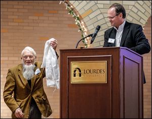Tom Williams of Louisville presents Woody Trautman, left, a Khata blessed by the Dalai Lama during the MultiFaith Banquet Sunday at the Franciscan Center at Lourdes University in Sylvania.