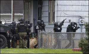 Police move to side of a home on Sibley St. in Toledo to fire tear gas into the basement.