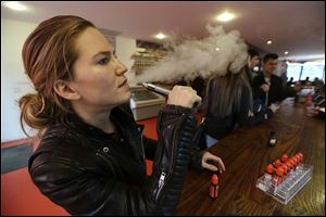 Talia Eisenberg, co-founder of the Henley Vaporium, uses her vaping device in New York in February. Under a New York City law taking effect today vaporizing devices will be treated the same as a tobacco-based cigarette. 