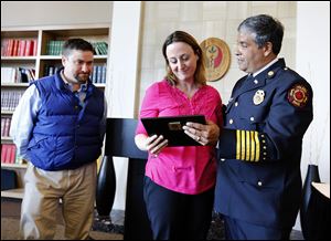 Toledo Fire Chief Luis Santiago, right, presents a plaque honoring deceased Toledo firefighter Stephen Machcinski to his sister, Beth Hoye, with her husband, Chris Hoye, left, during a University of Toledo Emergency Medicine Wall of Honor dedication ceremony at the Radisson Hotel on the UT Health Science Campus.   Plaques for Mr. Machcinski and fellow firefighter James ‘Jamie’ Dickman, who were killed while fighting a fire earlier this year, were dedicated Wednesday.