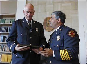 Toledo Fire Chief Luis Santiago, right, presents a plaque honoring deceased Toledo firefighter Jamie Dickman to Lt. George Simko during a University of Toledo Emergency Medicine Wall of Honor dedication ceremony today at the Radisson Hotel on the UT Health Science Campus.