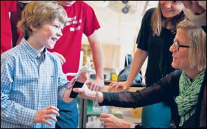 Eight-year-old Steele Songle smiles at his mother, Ellen, after trying on an artificial hand designed by high school engineering students.
