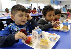 Biden Arias-Romers, 5, left, and Nathaniel Cossio-Boatwright, 6, right, eat lunch at the Patrick Henry Elementary School in Alexandria, Va.