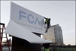 Workers unveil the Fiat Chrysler sign at Chrysler World Headquarters in Auburn Hills, Mich. The company aims to boost global sales from 4.4 million vehicles in 2013 to 7 million by 2018.
