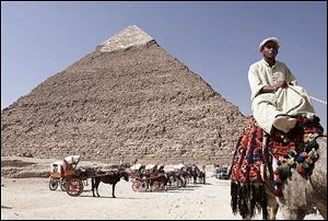 An Egyptian camel rider waits for customers at the historical site of the Giza pyramids, in front of the Khafre pyramid, near Cairo.