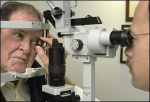 Dr. Ira Orgel examines the eyes of  John Taft for macular degeneration treatment.