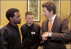 Park Inn banquet workers Darrell Madison, left, and Erik Dashner, center, admire a smart watch promoted by Fabiano Zamuner,the founder and CEO of Exetech Labs in Turin, Italy.