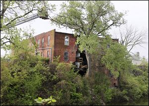 The rear of an unoccupied building at 20 Broadway gave way and practically split the structure in two just above Swan Creek in South Toledo on Monday.
