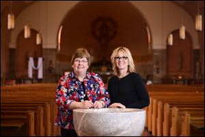 Director of adult faith formation Margaret McCready, left, and financial clerk Deb Grisier stand at the baptismal font at Gesu Roman Catholic Church in Toledo.