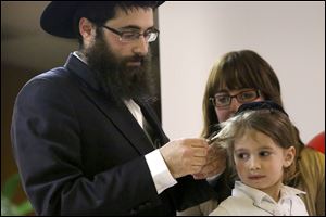 Rabbi Shmouel Matusof cuts a lock of his son Mendel’s hair during Mendel’s Upshernish, an inaugural haircutting ceremony, at Congregation Etz Chayim in West Toledo. Young Jewish boys receive their first haircut to celebrate their third birthday and mark the beginning of their formal education in the teachings of Judaism. This particular ceremony was also part of the Lag B’Omer celebration, a festival on the Jewish calendar.