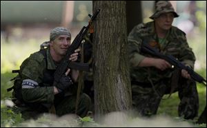 A pro-Russian gunman takes cover behind a tree during shooting near the airport, outside Donetsk, Ukraine, today.