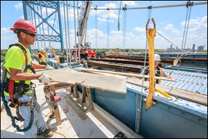 Eric Johnston of Norwalk passes a board to Marty Goon of Genoa, partially obscured, at work on the Anthony Wayne Bridge, which connects East Toledo to the rest of the city. Often called the High Level Bridge, it was built in 1931.