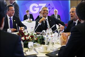 President Obama, center, laughs as he is seated with British Prime Minister David Cameron, left, and French President Francois Hollande during a G7 session in Brussels, Belgium, today.