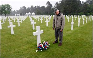 Paul Clifford, 70,  from Boston stands after placing flowers on the grave of Walter J. Gunther, Jr., the uncle of his best friend, in the Normandy American Cemetery and Memorial, in Colleville sur Mer, France, Wednesday.