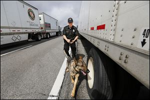 Trooper Ryan Stewart of the Ohio Highway Patrol’s criminal patrol team and his narcotics dog Oso search a tractor-trailer on the Ohio Turnpike near milepost 69. The driver and truck were released. 