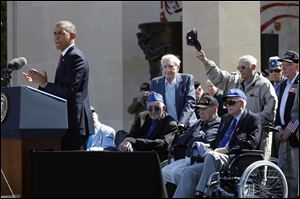 U.S. President Barack Obama, left, acknowledges veterans as he speaks at the Normandy American Cemetery, at Omaha Beach as he participates in the 70th anniversary of D-Day in Colleville sur Mer in Normandy, France.