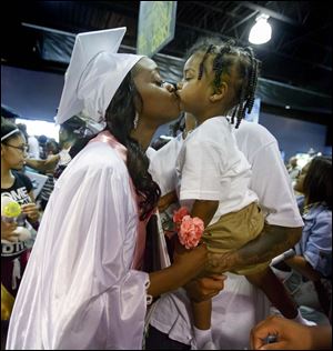 Cre'Ana Bell gets a kiss from son Cedyn Bell, 2, who is held by his father, Devon Woodard after commencement.