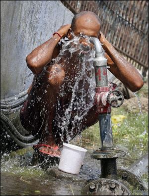 An Indian commuter cools off by bathing in water from a hose supplying water at a railway station today in Allahabad, India.