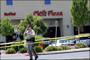 A Las Vegas police officer walks near the scene of a shooting in Las Vegas, Sunday. The spree began around 11:30 a.m. Sunday when a man and woman walked into CiCi's Pizza and shot two officers who were eating lunch, Las Vegas police spokesman Larry Hadfield said.