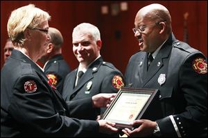 Barb Aldrich presents firefighter Kevin Gordon, right, the Life Saving Award as he happily thanks her for it during an awards ceremony to recognize the accomplishments of city firefighters. Craig Ellis, center, also received the Life Saving Award.