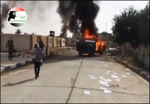 This image made from video posted by Iraqi0Revolution, a group supporting the al-Qaeda breakaway Islamic State of Iraq and the Levant,  on Wednesday, shows militants on Al-Sharqat base north of Tikrit, Iraq.