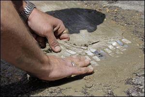 Bachor carefully removes cheese cloth from a finished art piece that he installed to cover a pothole on a street in Chicago.