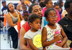 Keith Dandridge EL of Toledo center, holds onto his daughters Khloe Keith Dandridge El, left, 4, and Ryleigh Keith Dandridge EL, right, 6, while they listen to a water safety seminar given by Wanda Butts at  St. Francis de Sales High School on  Saturday.