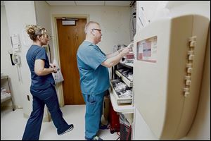 Kevin Cischke refills medications and medical tools during his shift as Jennifer Jagielski of Toledo, a licensed practical nurse, passes by.