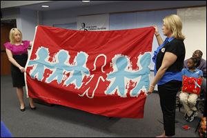 Lucas County Children Services case workers Christina DeSilvis, left, and Danielle Stroble with the Child Abuse flag.