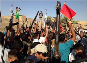 Shiite tribal fighters raise their weapons and chant slogans against the al-Qaeda-inspired Islamic State of Iraq and the Levant in the east Baghdad neighborhood of Kamaliya, Iraq, Sunday.
