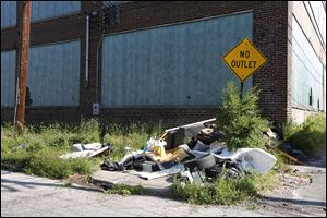 Trash is dumped in front of a boarded-up  building on Castle Drive between Maplewood and Glenwood avenues in Toledo.