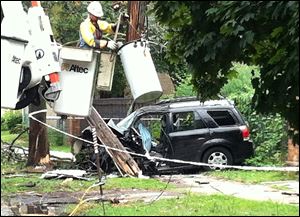 A Toledo Edison worker secures a pole in the 500 block of West Bancroft Street in Toledo after a driver crashed into it while fleeing police Thursday. The driver was killed in the crash, police said.
