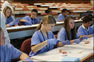 Chole Lammers, 14, of Miller City, center, practices suturing a pig’s foot during class at the University of Toledo’s Health Science Campus, the former Medical College of Ohio. This was the 17th year of UT’s annual CampMed program. Forty-five students going into ninth grade participated this year.