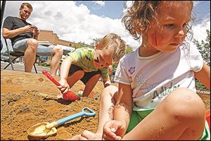 Twins Atticus, left, and Madeline play in a giant sandbox during last year’s Sand-Tastic! at Levis Commons.