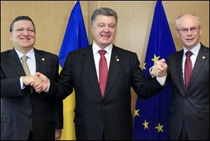 Ukraine's President Petro Poroshenko, center, poses with European Commission President Jose Manuel Barroso, left, and European Council President Herman Van Rompuy, right, during an EU Summit in Brussels today.