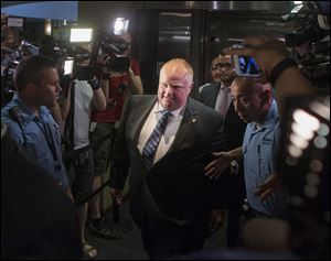 Toronto Mayor Rob Ford, center, is greeted by a media throng as returns to his office at city hall today in Toronto.