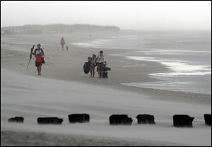 Clouds and rains move in as beachgoers leave Freeman Park at the north end of Carolina Beach, N.C., today.