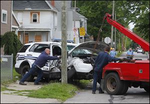 City workers try to remove a Toledo police vehicle that was broadsided at 4:43 a.m. on Thursday.