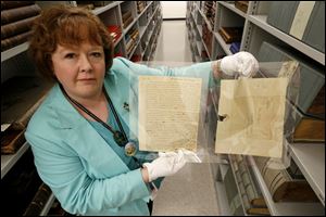 Jill Clever, manager of the Local History and Genealogy Department at the Toledo-Lucas County Public Library, holds an original letter and envelope written by Thomas Jefferson.