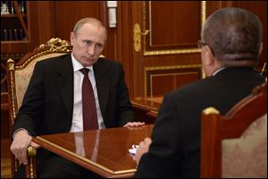 Russian President Vladimir Putin listens Russia's economic development minister Alexei Ulyukayev, right, in Moscow's Kremlin on Monday.