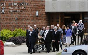 Pallbearers carry Father Gerald Robinson's casket from his funeral service today at St. Hyacinth Church in Toledo.