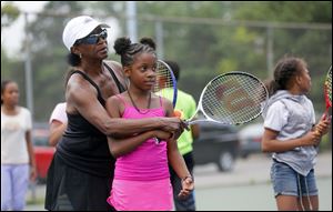 Ethel Parker helps Tatiyana Esmond, 8, with her forehand earlier this month during Ethel Parker's Tennis Camp at Jermain Park in Toledo.