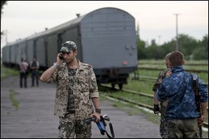 A pro-Russian rebel speaks on the phone as a refrigerated train loaded with bodies of the passengers departs the station in Torez, eastern Ukraine today, 9 miles from  the crash site of Malaysia Airlines Flight 17.