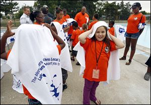 Youngsters from the Friendly Center, including Chloe Wentworth, 8, facing camera, try out donated towels after the opening of the Jamie Farr Park Pool in North Toledo on Wednesday. 