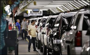 An auto worker inspects finished SUVs coming off the assembly line at the General Motors auto plant in Arlington, Texas. 