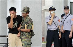 A relative, left, of a victim in the TransAsia Airways flight GE222 crash is consoled by a soldier during a funeral service on the Taiwan island of Penghu, today.