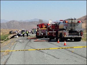 Emergency personnel work at the site of a collision between a pickup truck and a small airplane which was making an emergency landing on Nevada Route 445, about 20 miles north of Reno, Nev. on Saturday, July 26, 2014. Police said all four occupants of both vehicles escaped with minor injuries.