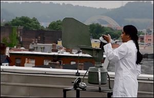 Asha Patel, am immunology researcher, holds a collector from the Burkard Spore Trap on the roof of Allegheny General Hospital in Pittsburgh.